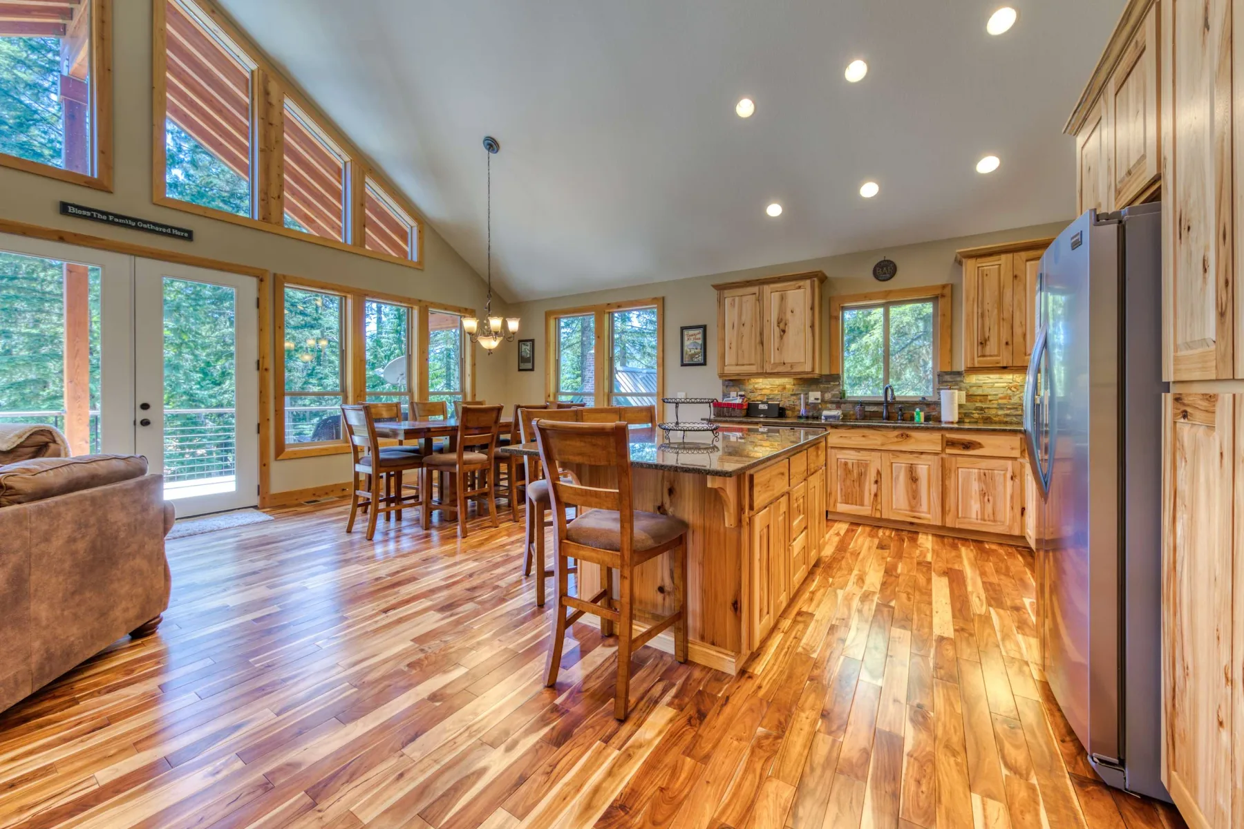 A bright open-plan kitchen and dining area with large windows and wood cabinetry.