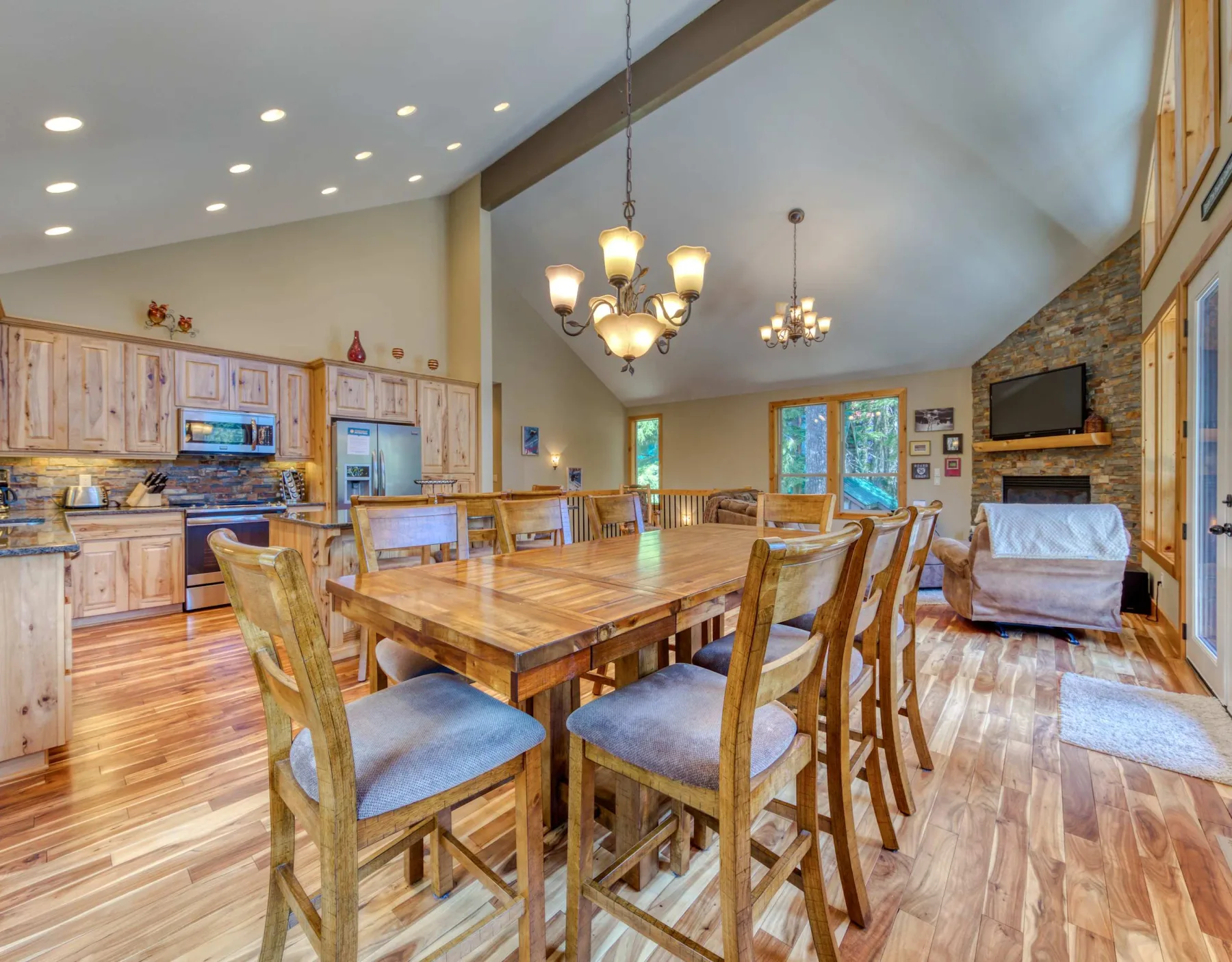 A dining area with a large wooden table and chairs beside an open kitchen.