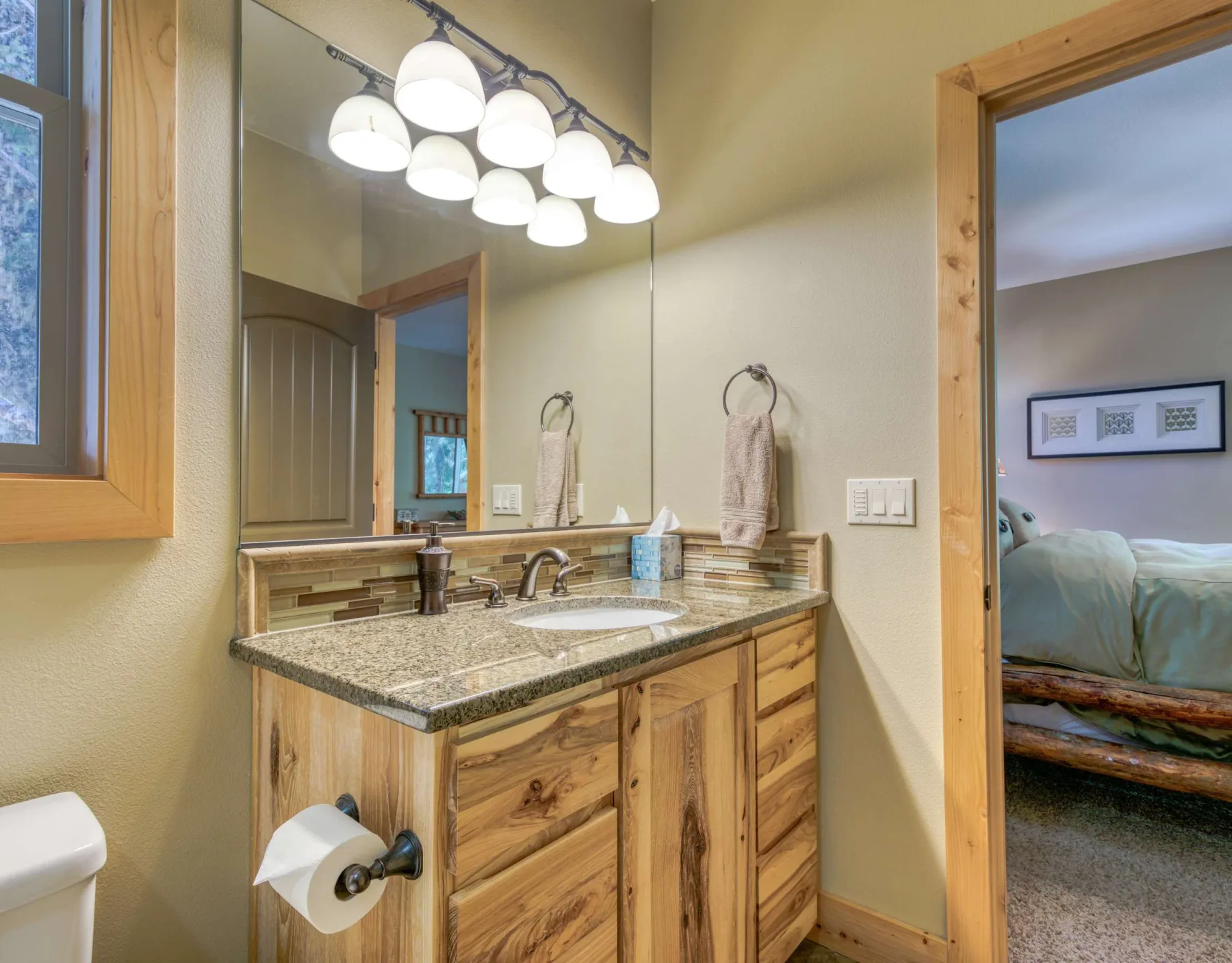 A bathroom vanity with a sink and large mirror sits beside an open doorway.