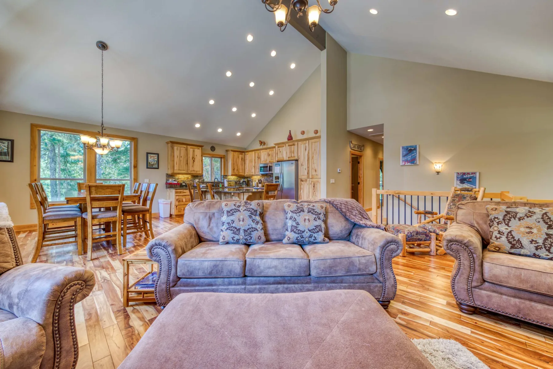 A spacious living room with seating, a dining area, and a high vaulted ceiling.