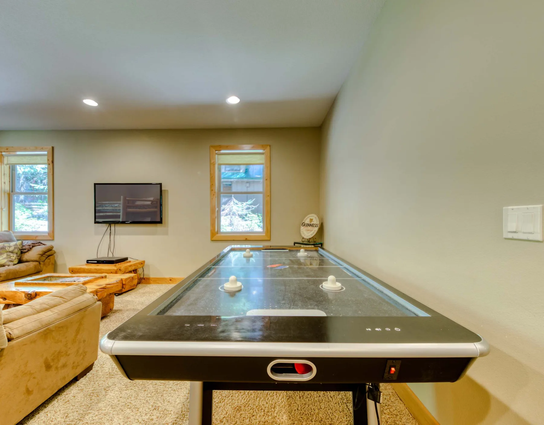 A game room with a pool table, seating, and a wall-mounted television.
