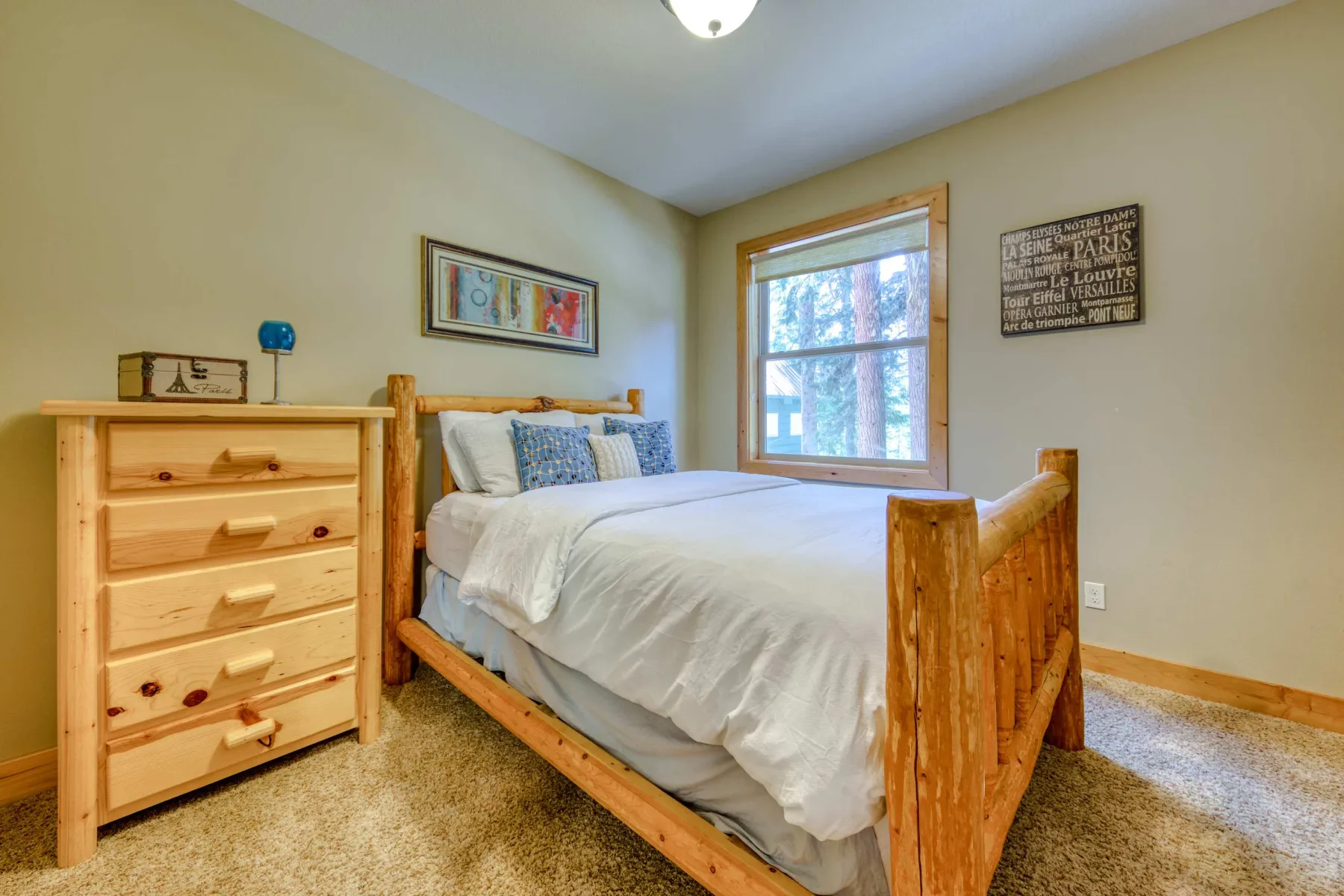 A bedroom with a wooden bed, white bedding, and a window.