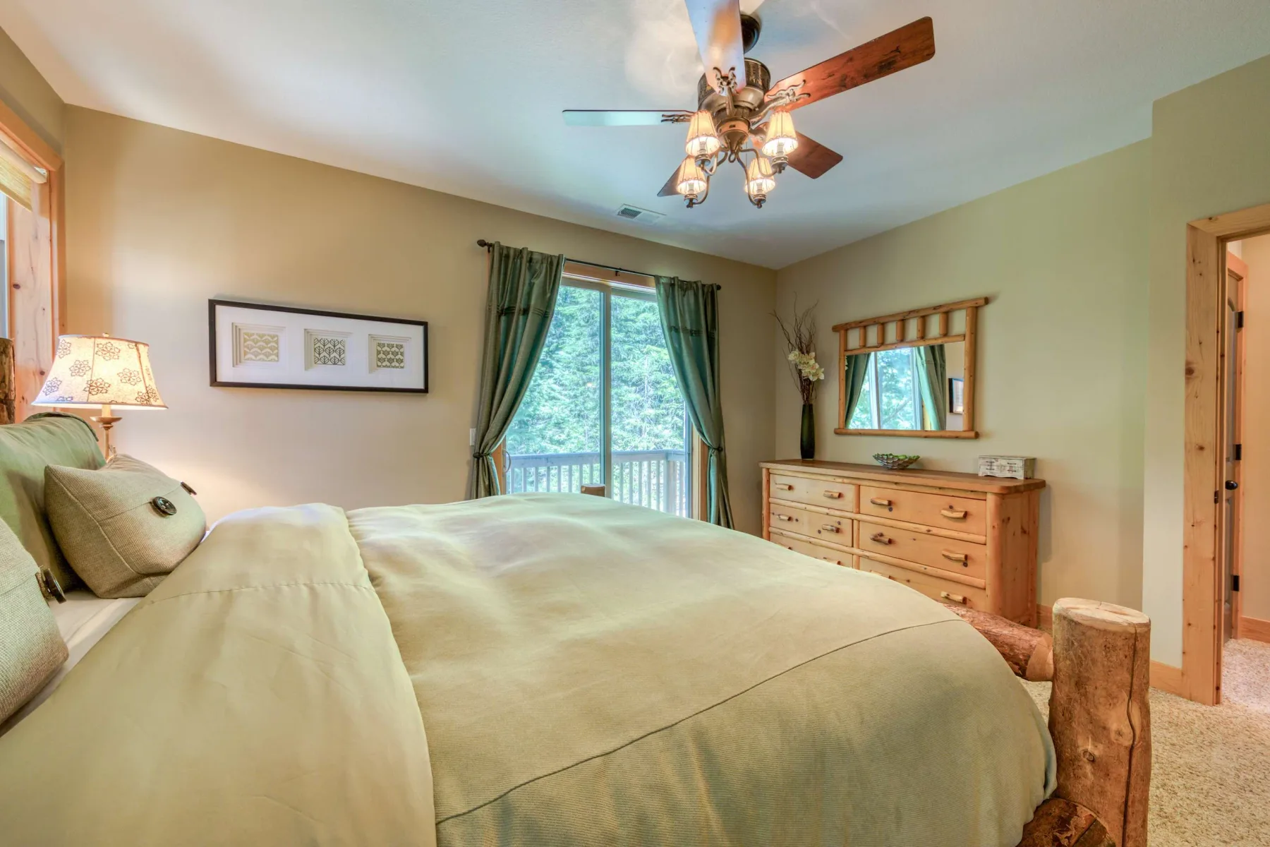 A bedroom with a neatly made bed, green curtains, and a wooden dresser.