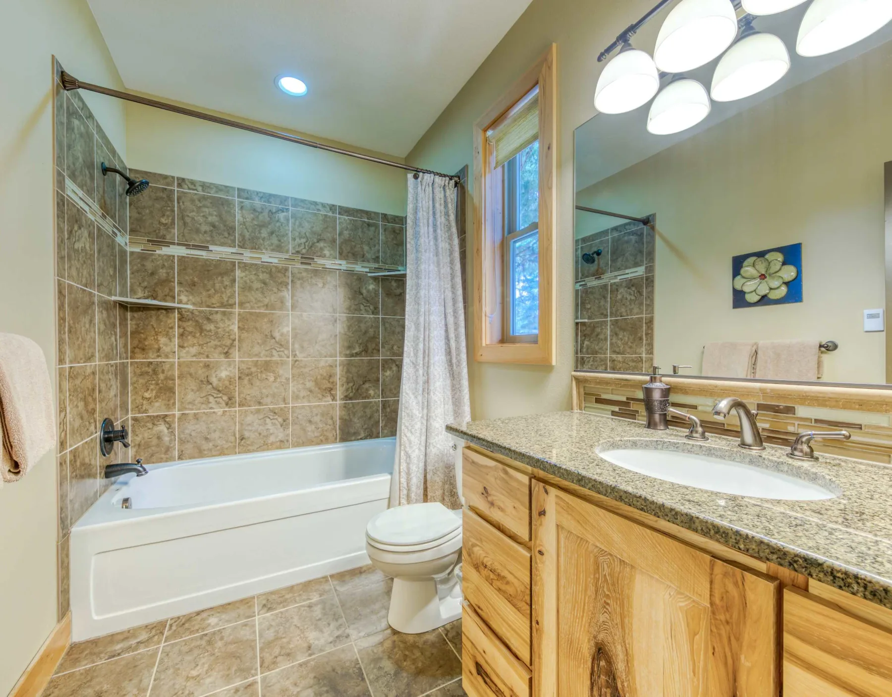A bathroom with a bathtub and a wooden vanity beside a window.