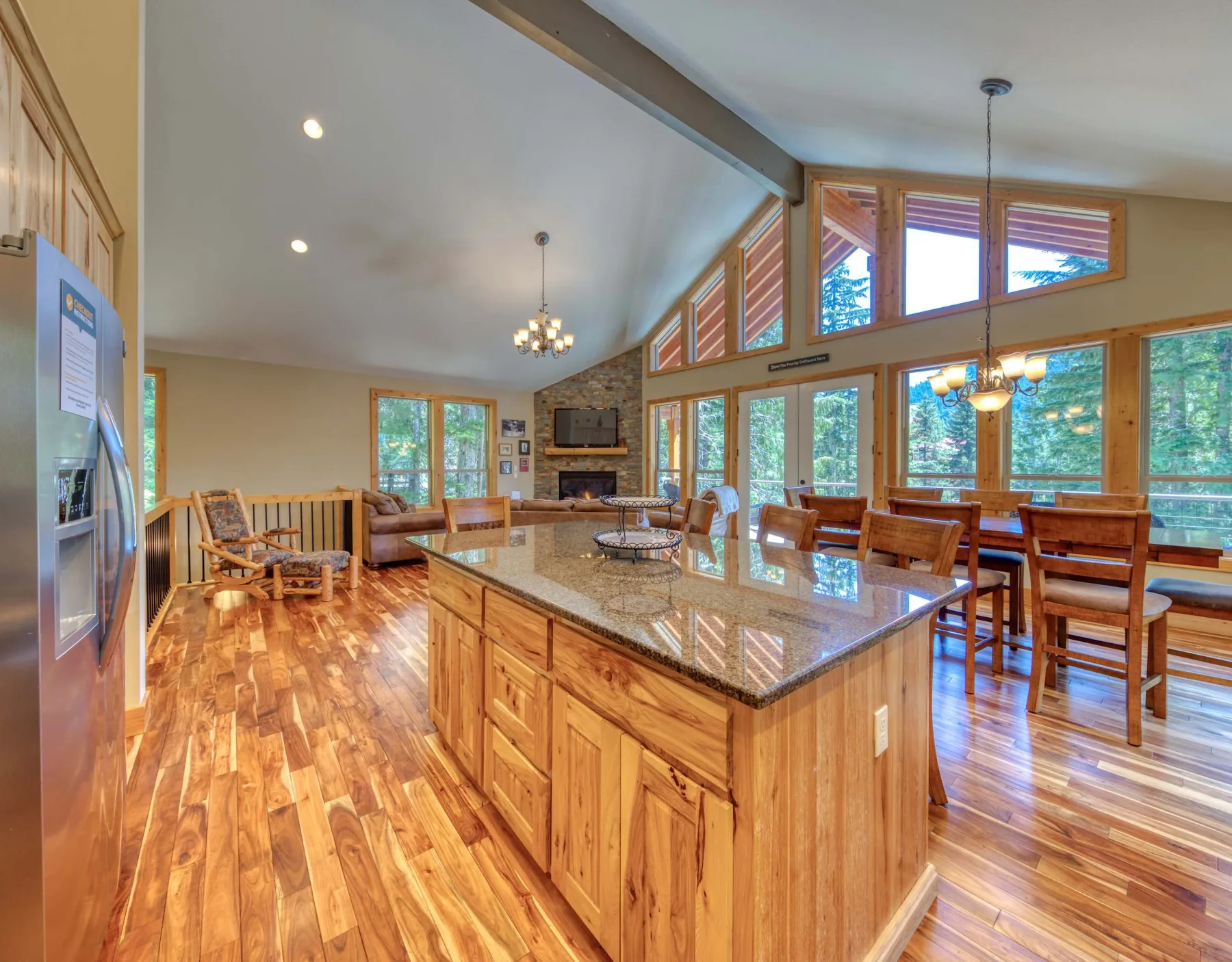 A spacious open-plan kitchen and dining area with a wood island and large windows.