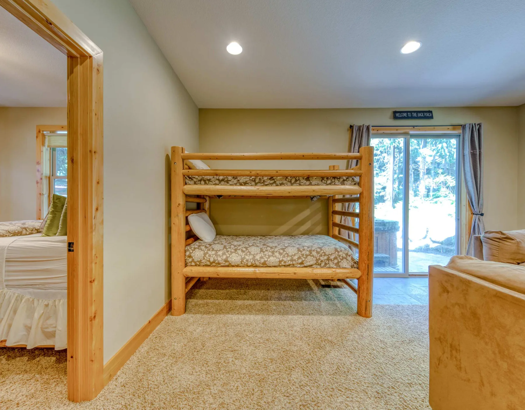 A carpeted bedroom features a wooden bunk bed beside a large window.