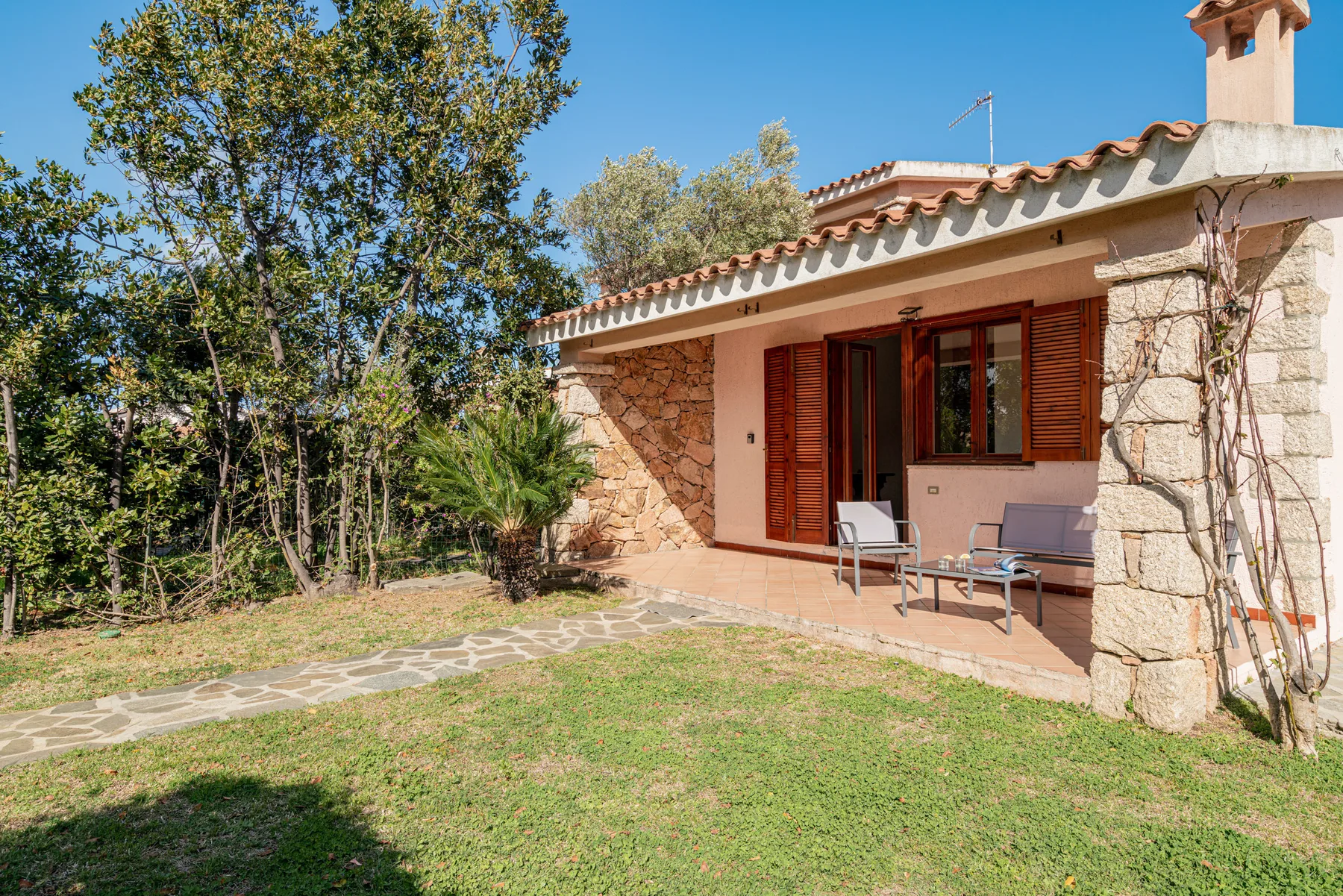 Una casa de piedra da a un patio con asientos al aire libre y un jardín de césped.