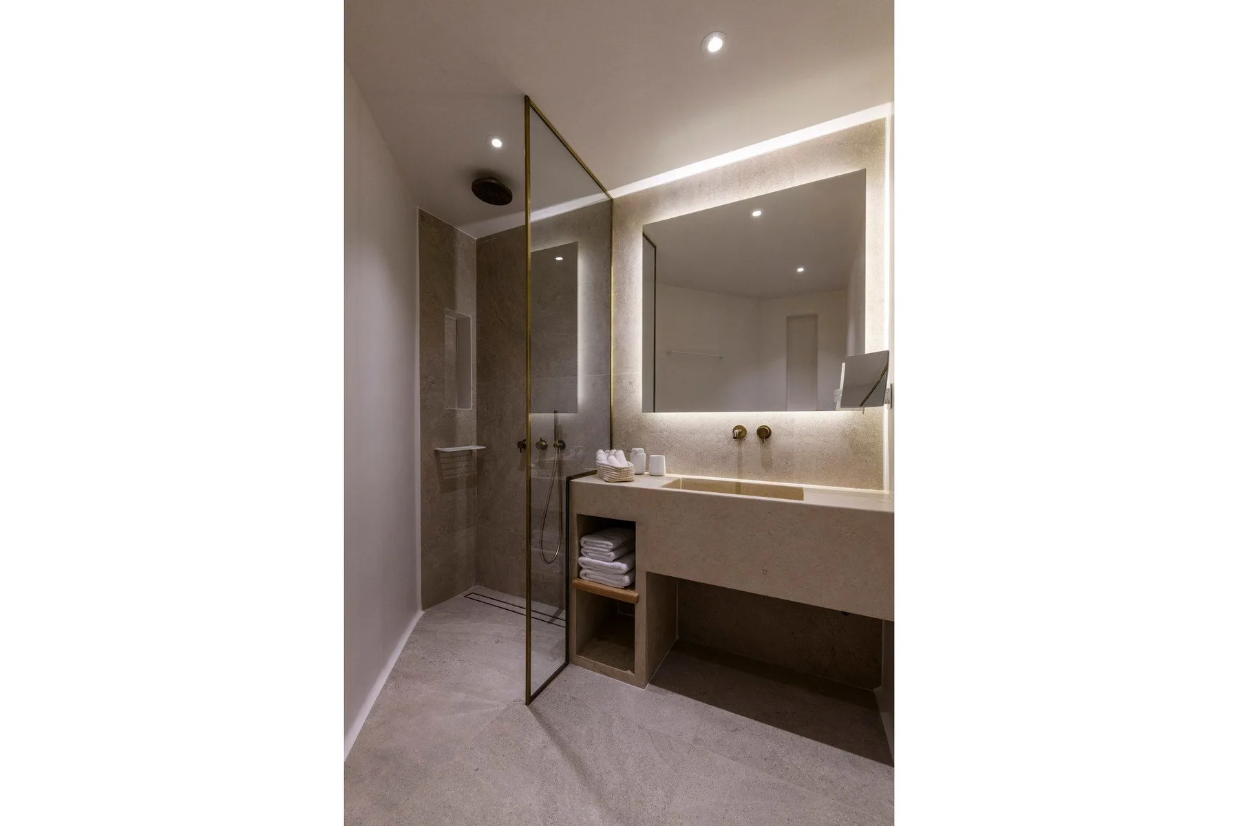 Un baño moderno con una ducha de vidrio y un espejo grande iluminado.