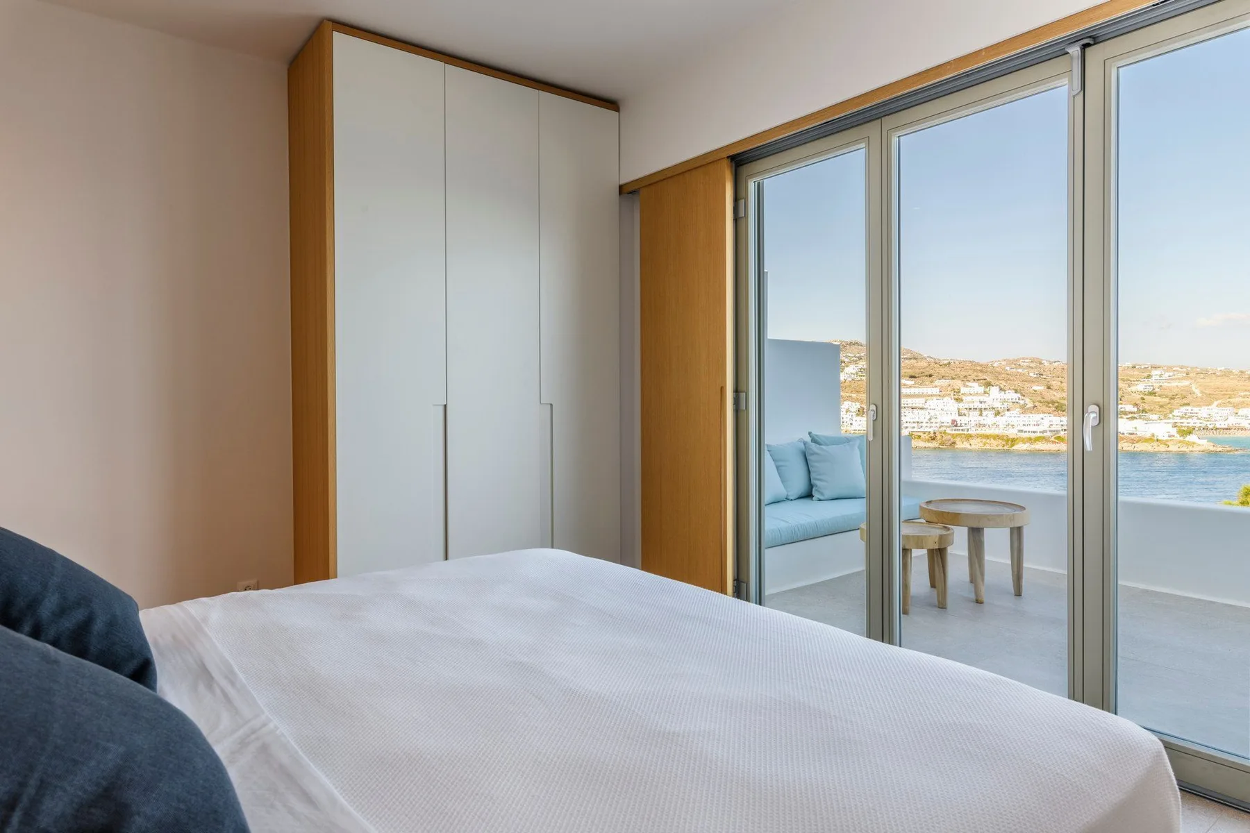 Un dormitorio con una cama junto a puertas corredizas de vidrio con vistas al agua.