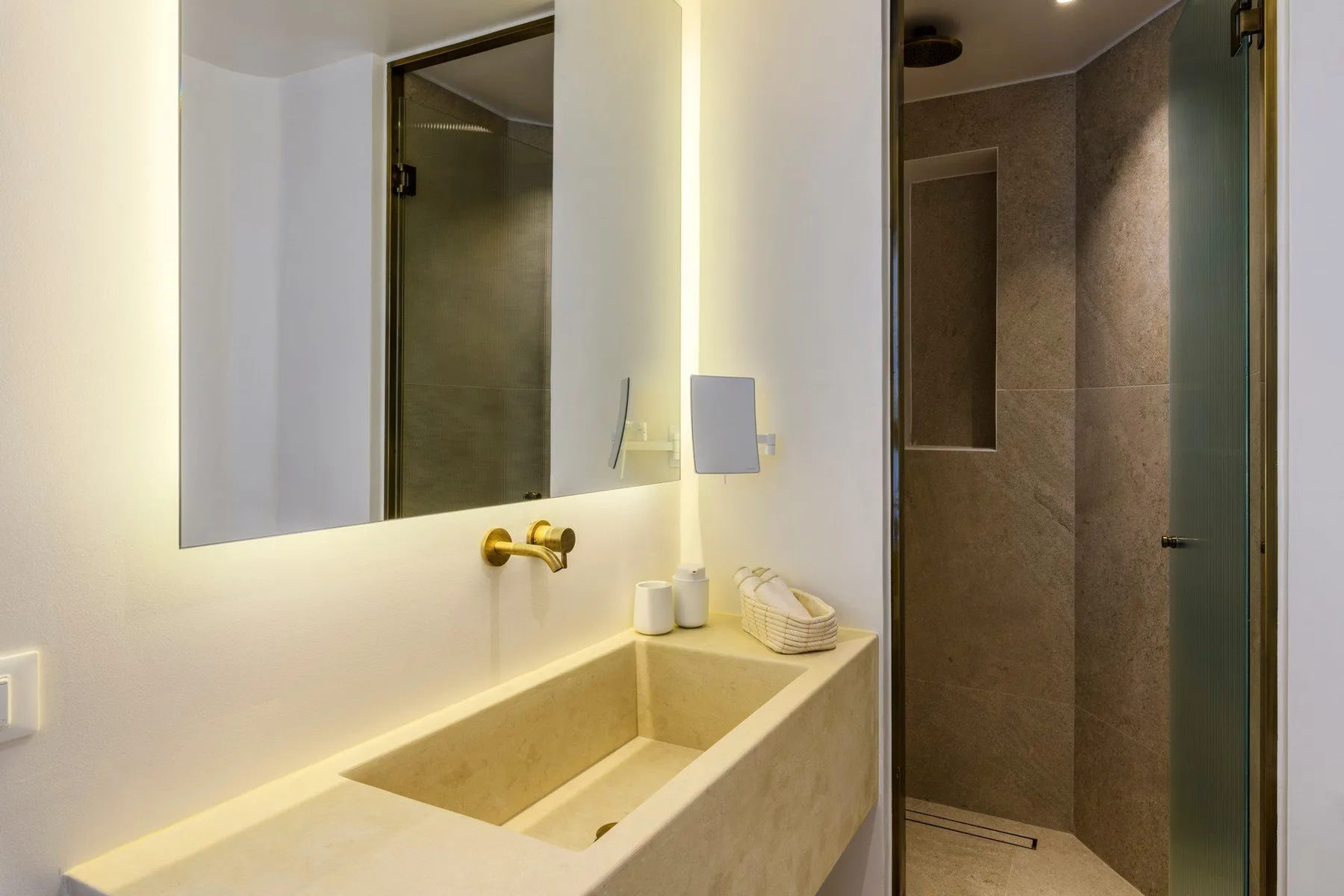 Un lavabo de baño con fregadero rectangular junto a una ducha revestida de azulejos.