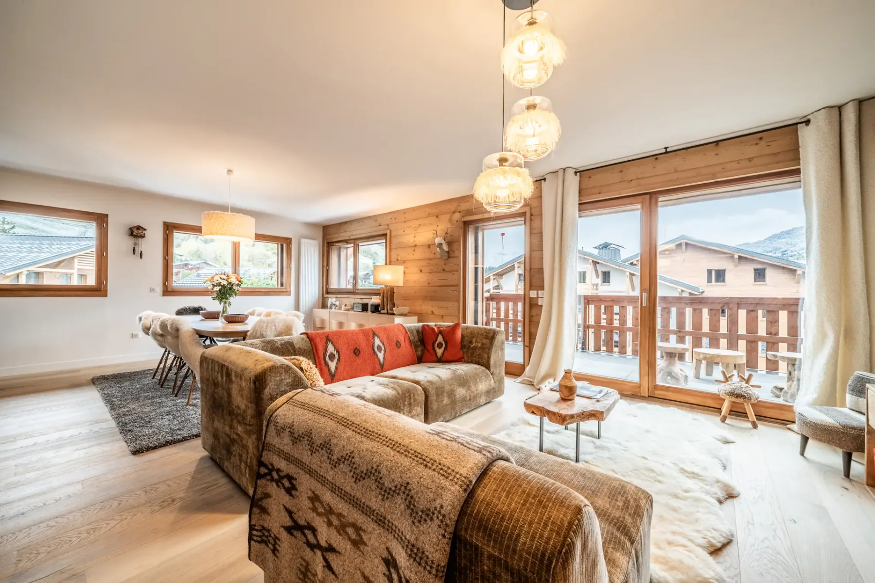 A bright living room with seating, a wooden coffee table, and large windows.