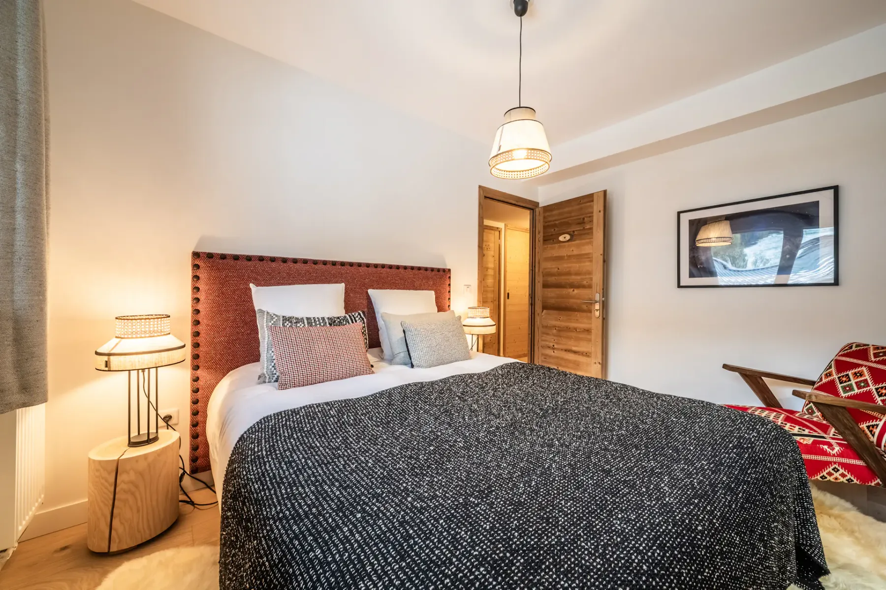 A bedroom with a bed, patterned bedding, and a wooden door.
