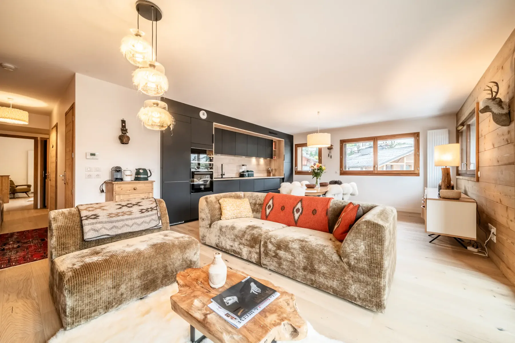 A living room with a sofa, armchair, and adjoining kitchen.