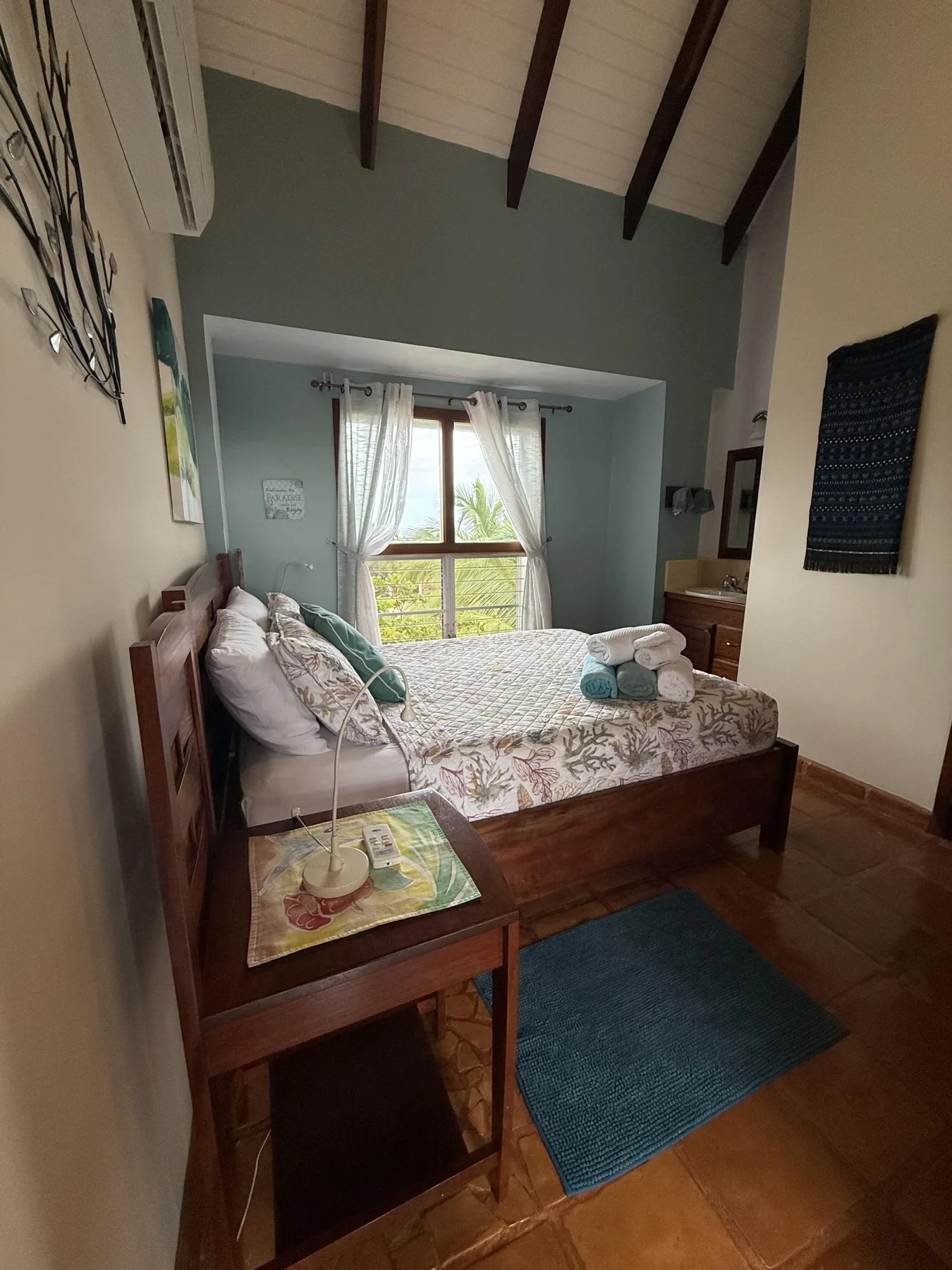 Un dormitorio con una cama de madera, ropa de cama estampada y una ventana con cortinas.