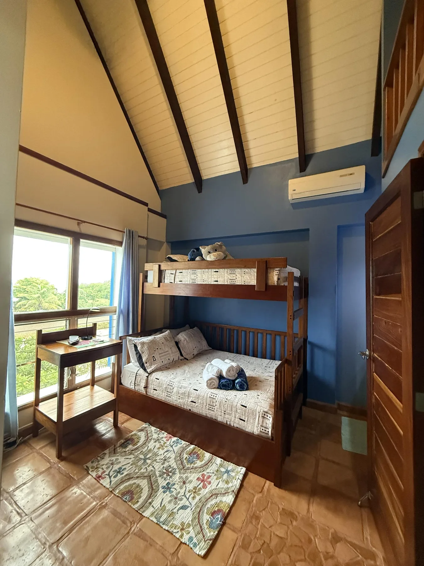 Un dormitorio compacto con literas, un escritorio y ventanas grandes.