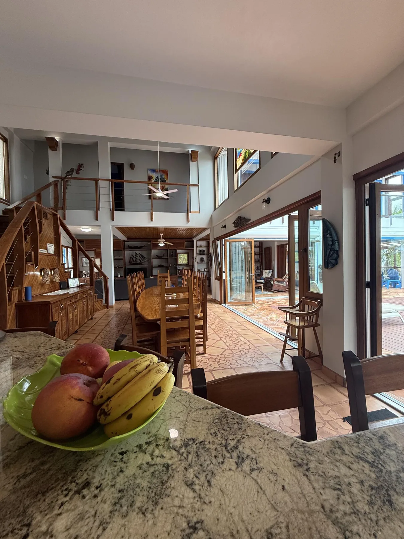Un amplio comedor con una larga mesa de madera y un frutero en primer plano.