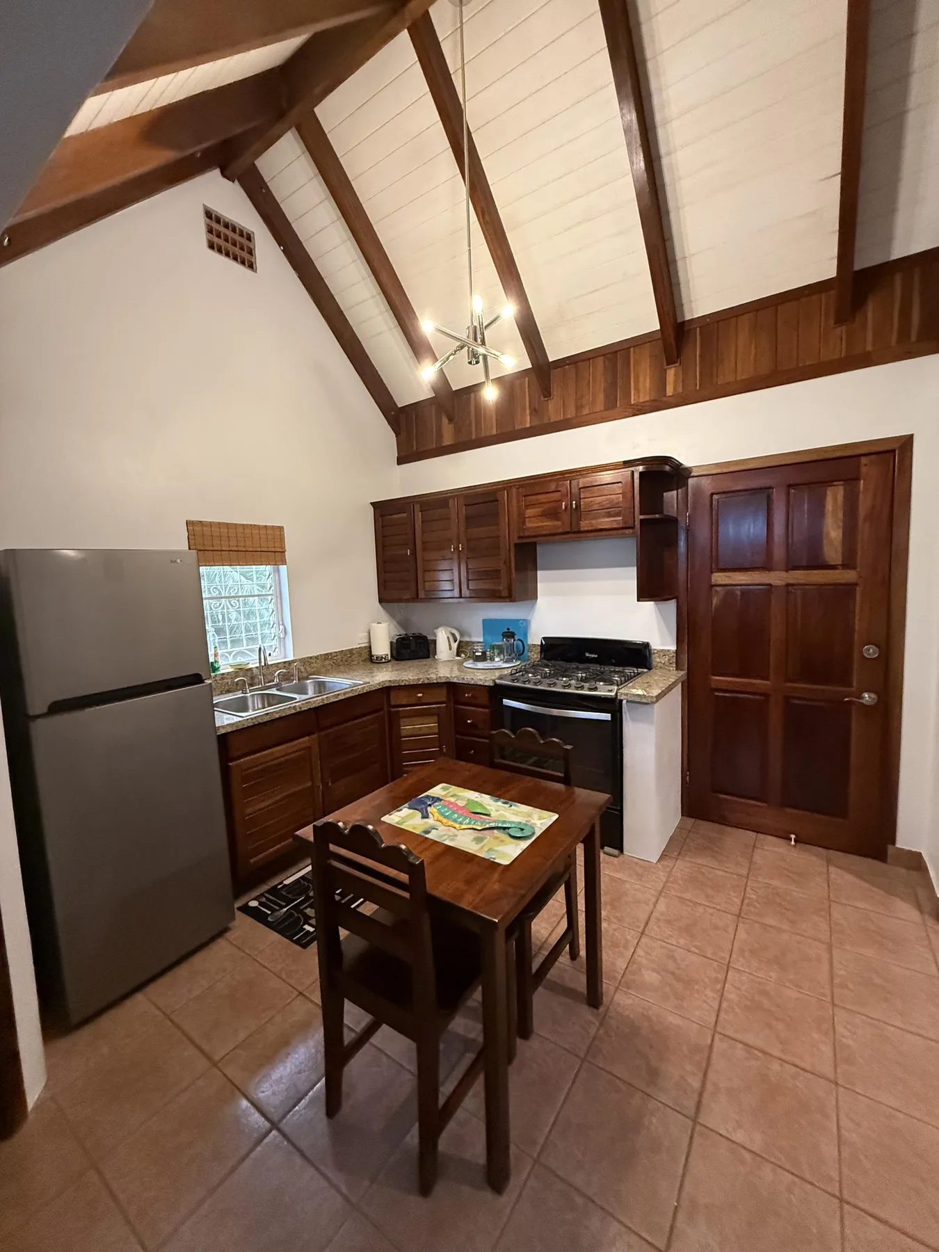 Una cocina compacta con gabinetes de madera, una estufa y una pequeña mesa de comedor.