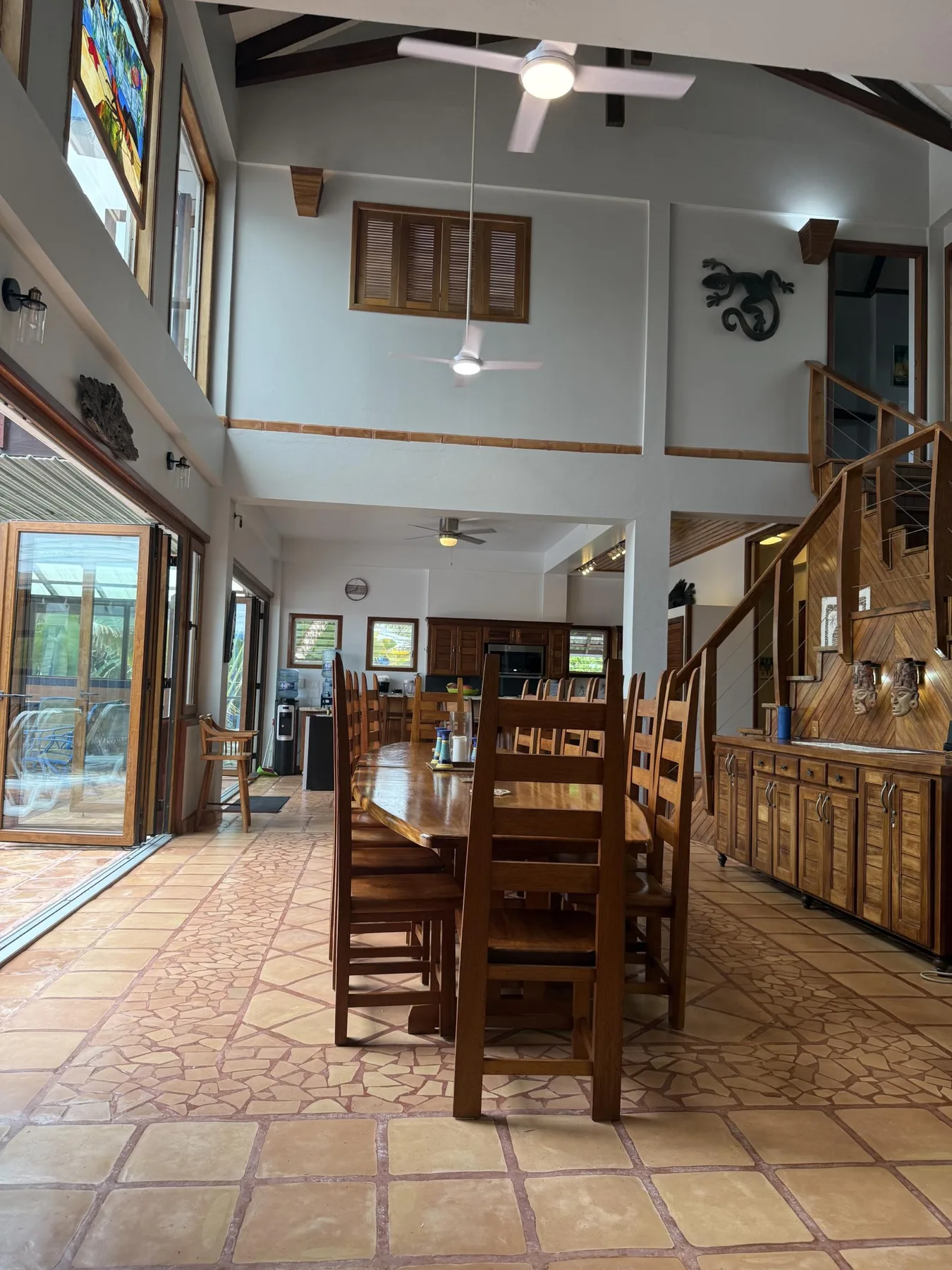 Comedor con una mesa larga de madera y sillas bajo un techo alto.