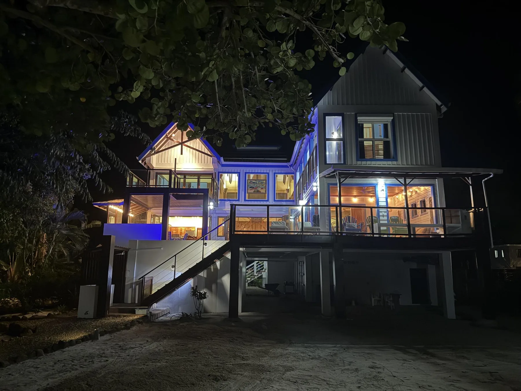 Una casa grande está iluminada de noche, con balcones y ventanas resplandecientes.