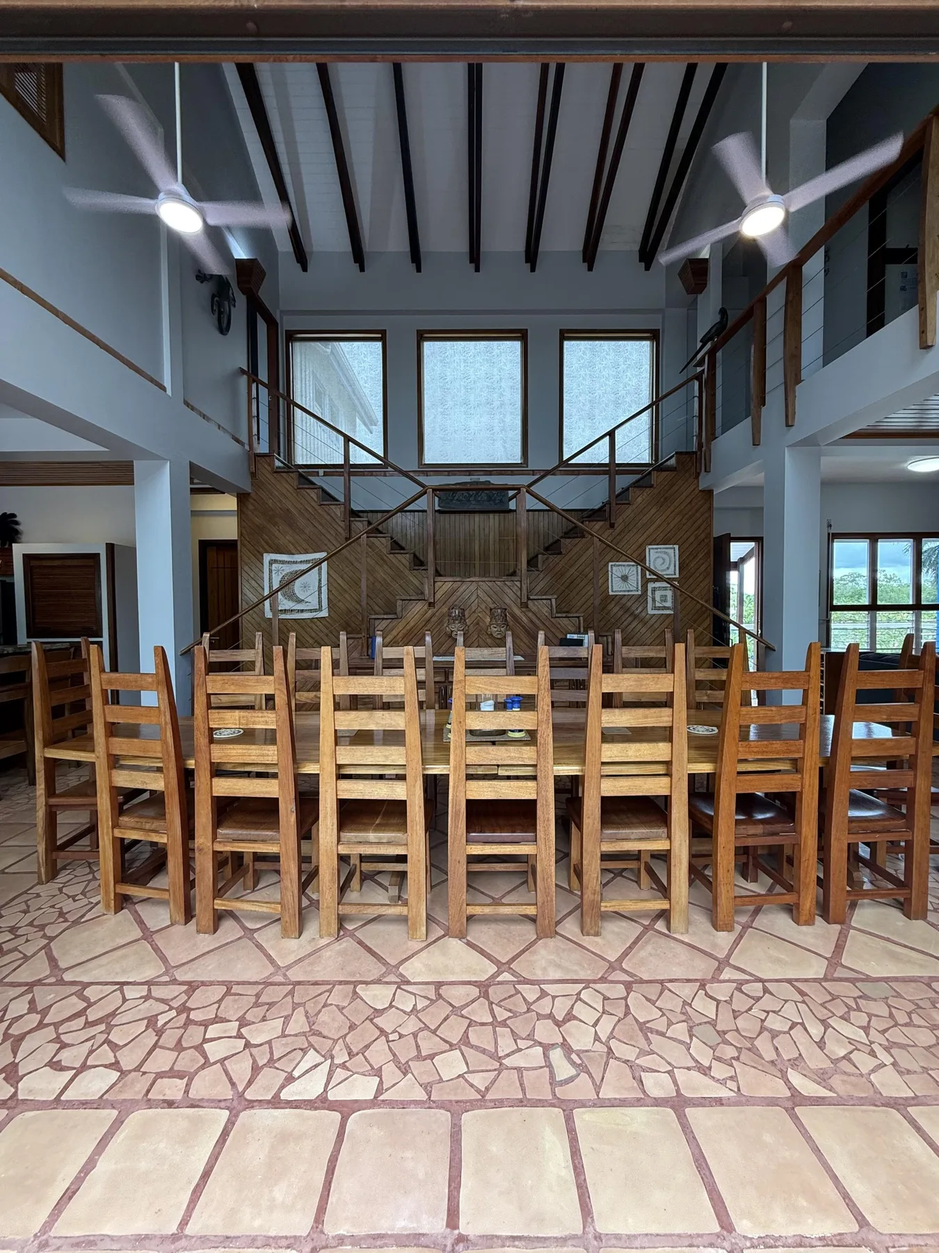 Un amplio comedor con mesas y asientos de madera bajo vigas expuestas en el techo.