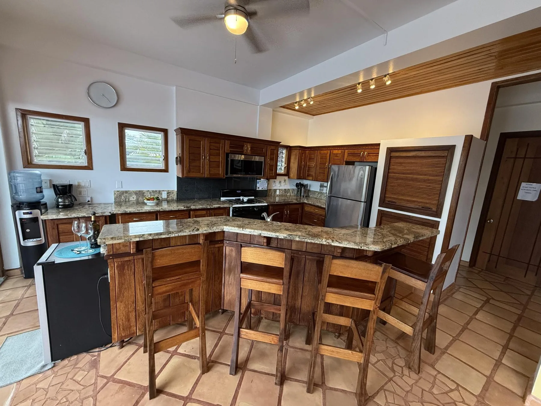 Una cocina con gabinetes de madera, una barra central y asientos.