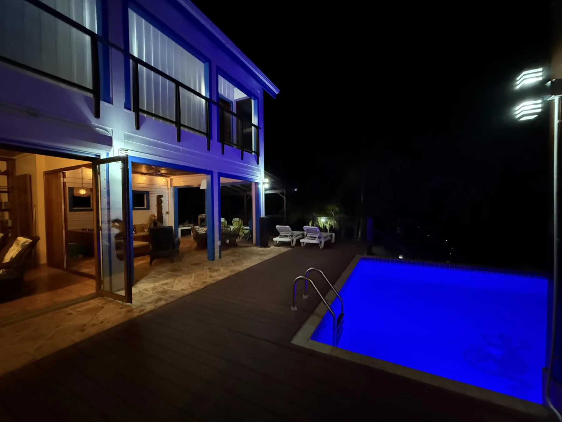 Una casa moderna y una piscina iluminada se ven de noche.
