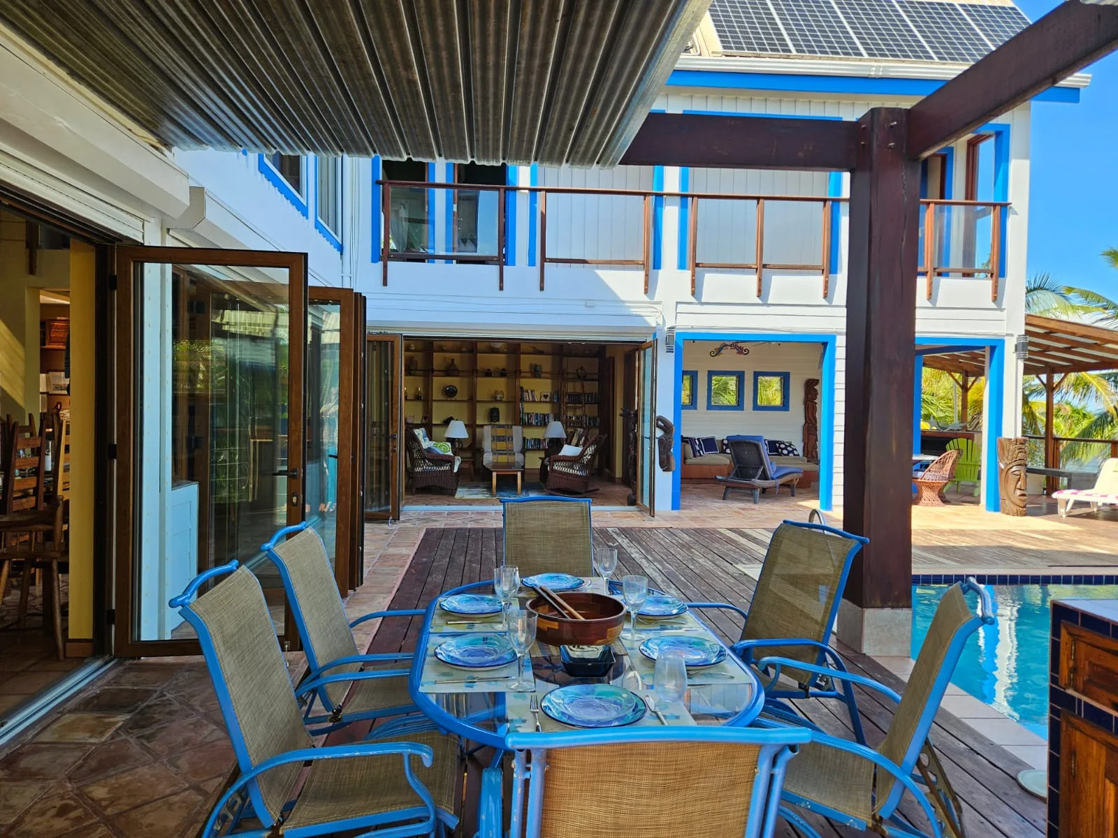 Una zona de comedor al aire libre con mesa de vidrio y asientos junto a una piscina.