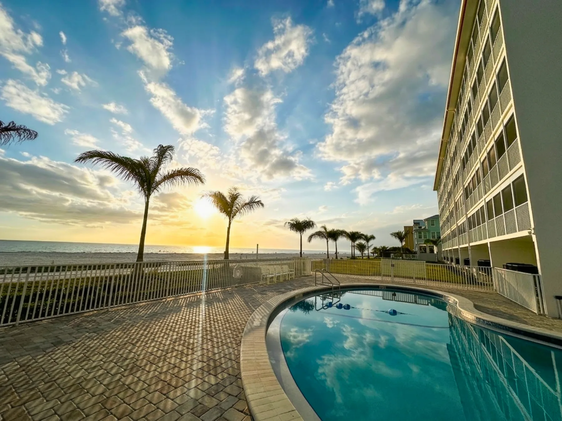 Shared amenity: A pool beside a beachfront building, with palm trees and the ocean beyond.