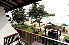 Espacio representativo del hotel: Un patio exterior a la sombra da a una playa con sombrillas y asientos.