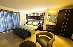 Espacio representativo del hotel: Un dormitorio de hotel con cama, asientos y cortinas oscuras.