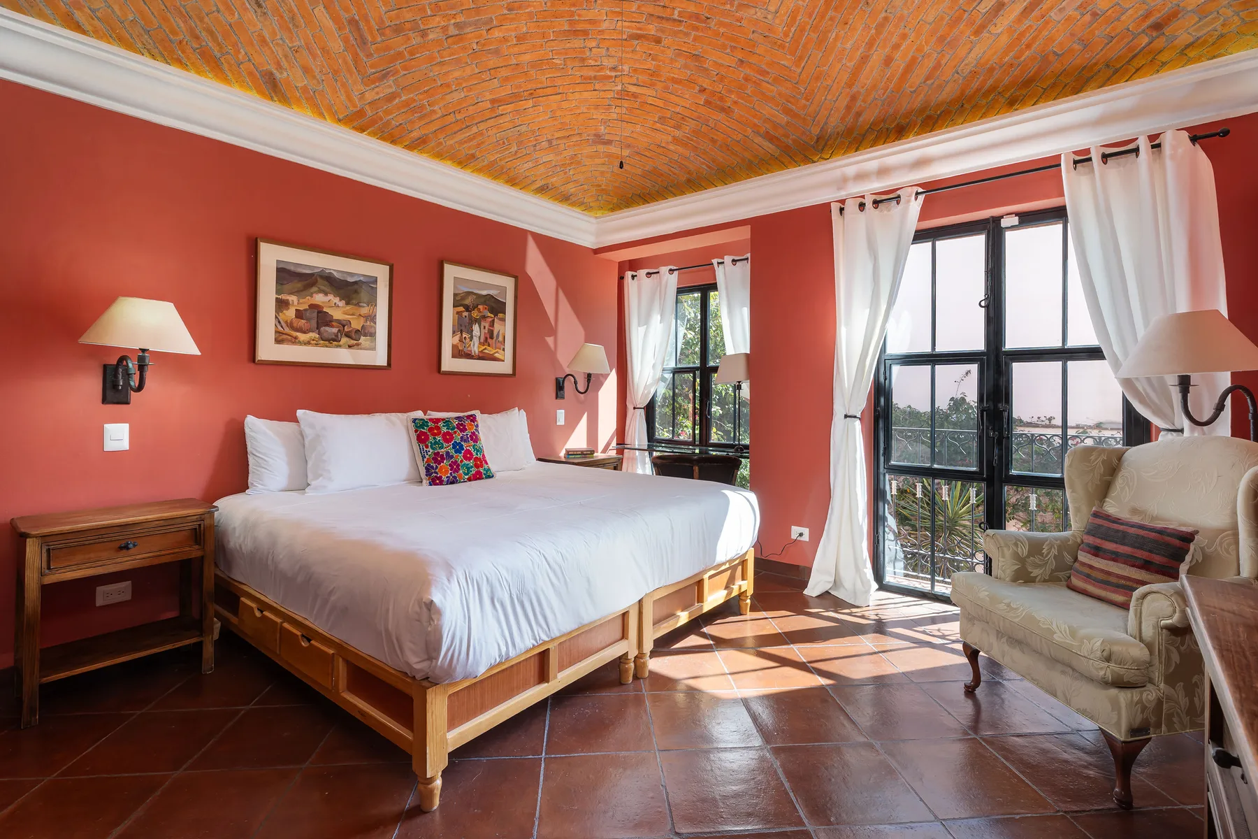 A bedroom with a bed and seating beside tall windows.