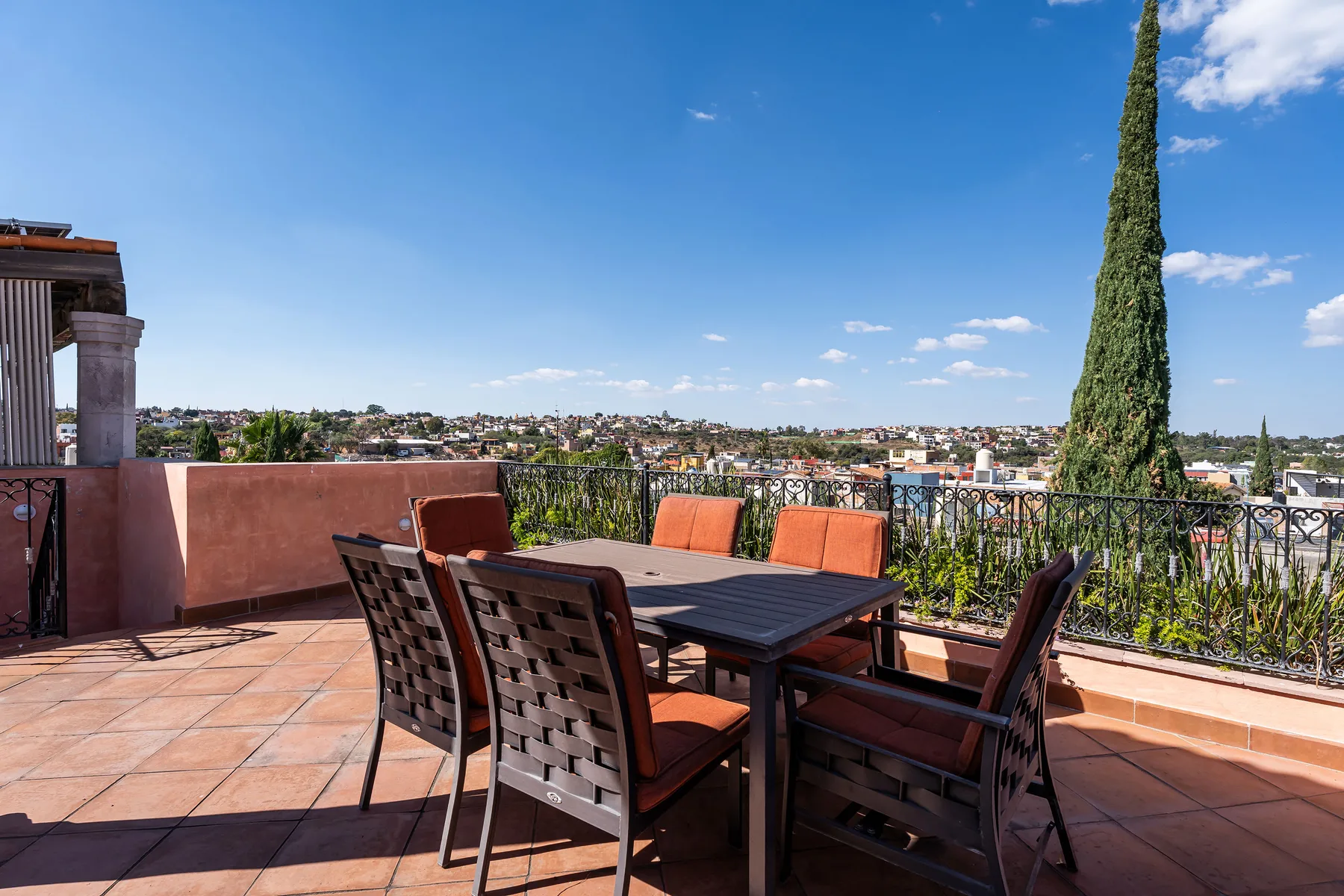 A rooftop terrace with outdoor seating overlooks a sprawling city.