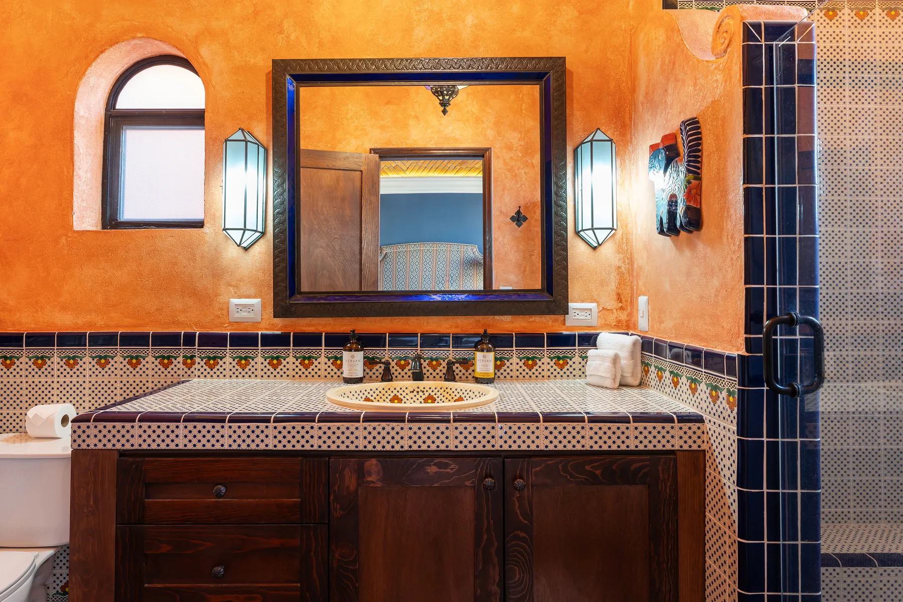 A bathroom vanity with a large mirror and tiled countertop.