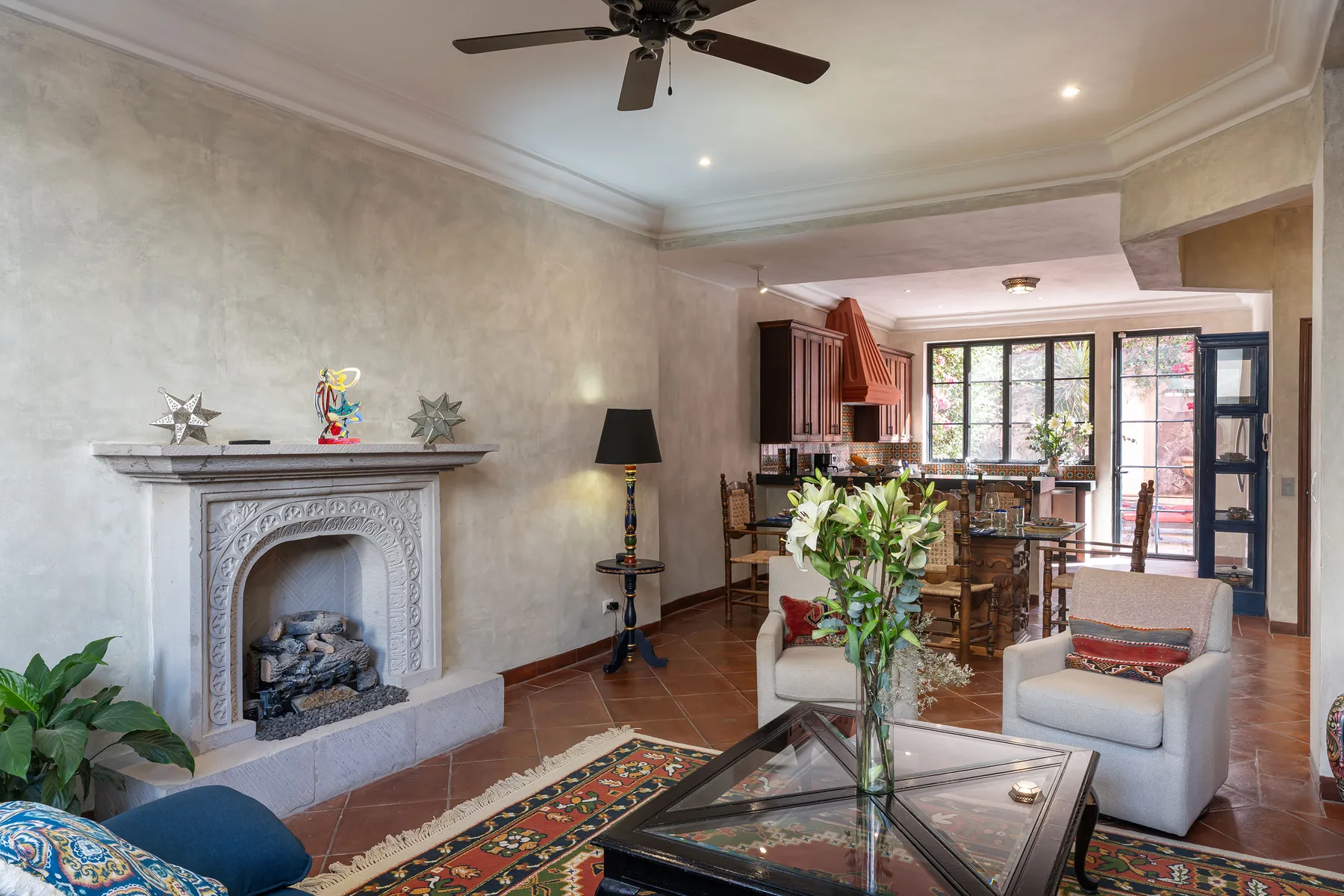 A living room with a fireplace, seating, and a dining area beyond.