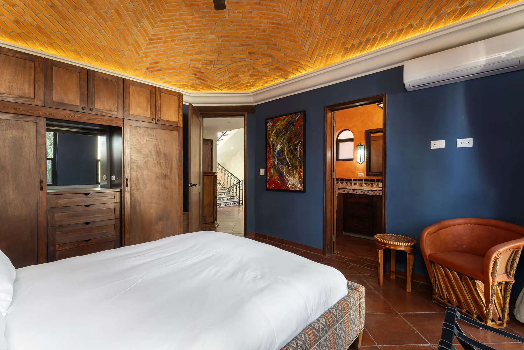 A bedroom with a large bed, built-in wooden cabinets, and a brick ceiling.