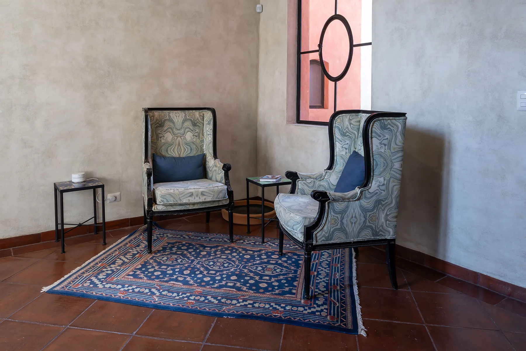 A sitting area with patterned seating arranged around a small rug.