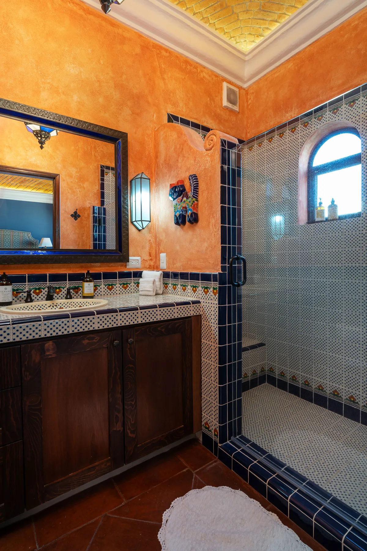 A tiled bathroom with a vanity, mirror, and glass shower area.