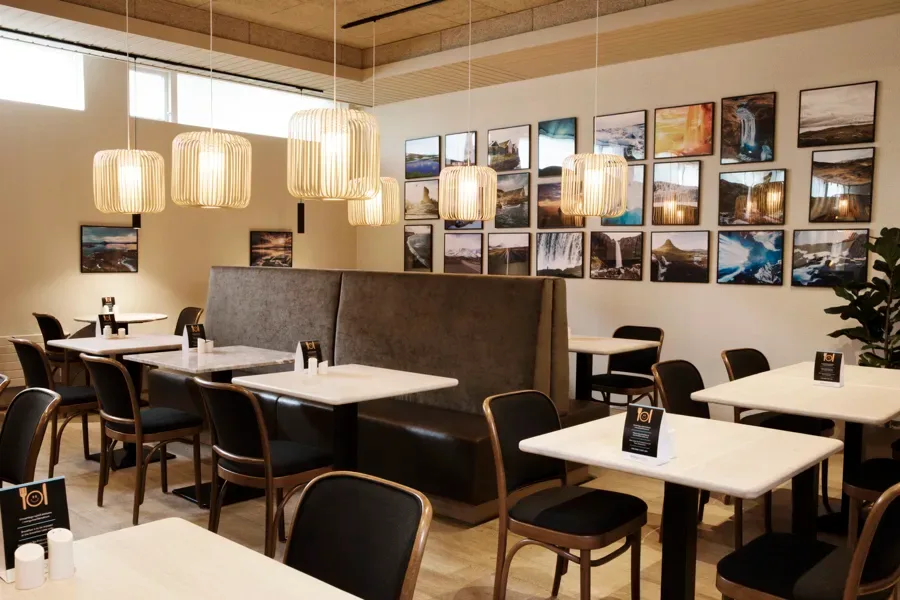 Espacio representativo del hotel: Un comedor con mesas y asientos bajo lámparas colgantes.