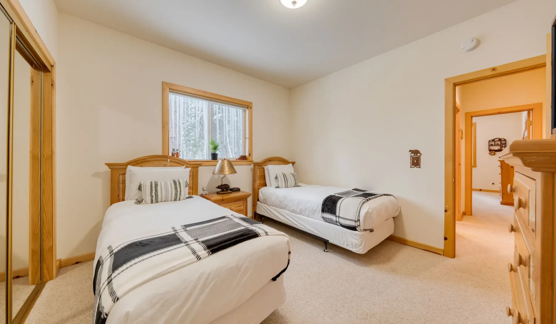 Dormitorio con dos camas, ropa de cama estampada a juego y una ventana.