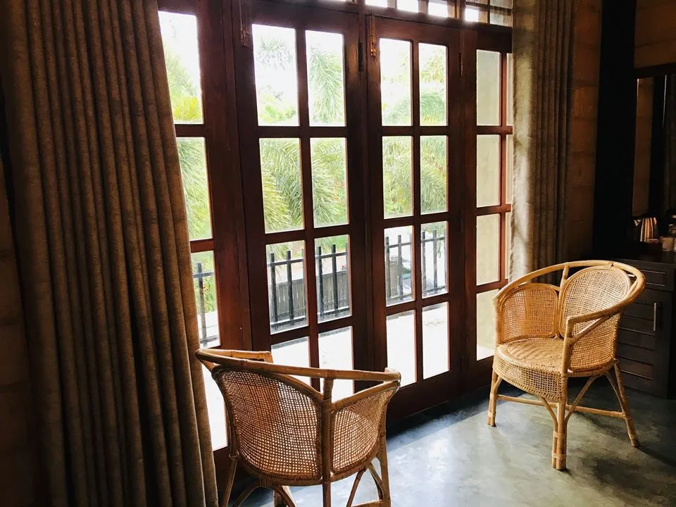 Espacio representativo del hotel: Una zona de asientos con sillas de mimbre junto a puertas altas con paneles de vidrio.