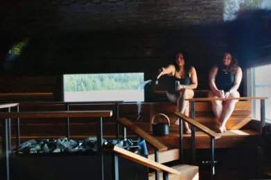Representative hotel space: A dim sauna room with two people seated beside a heated stone bed.