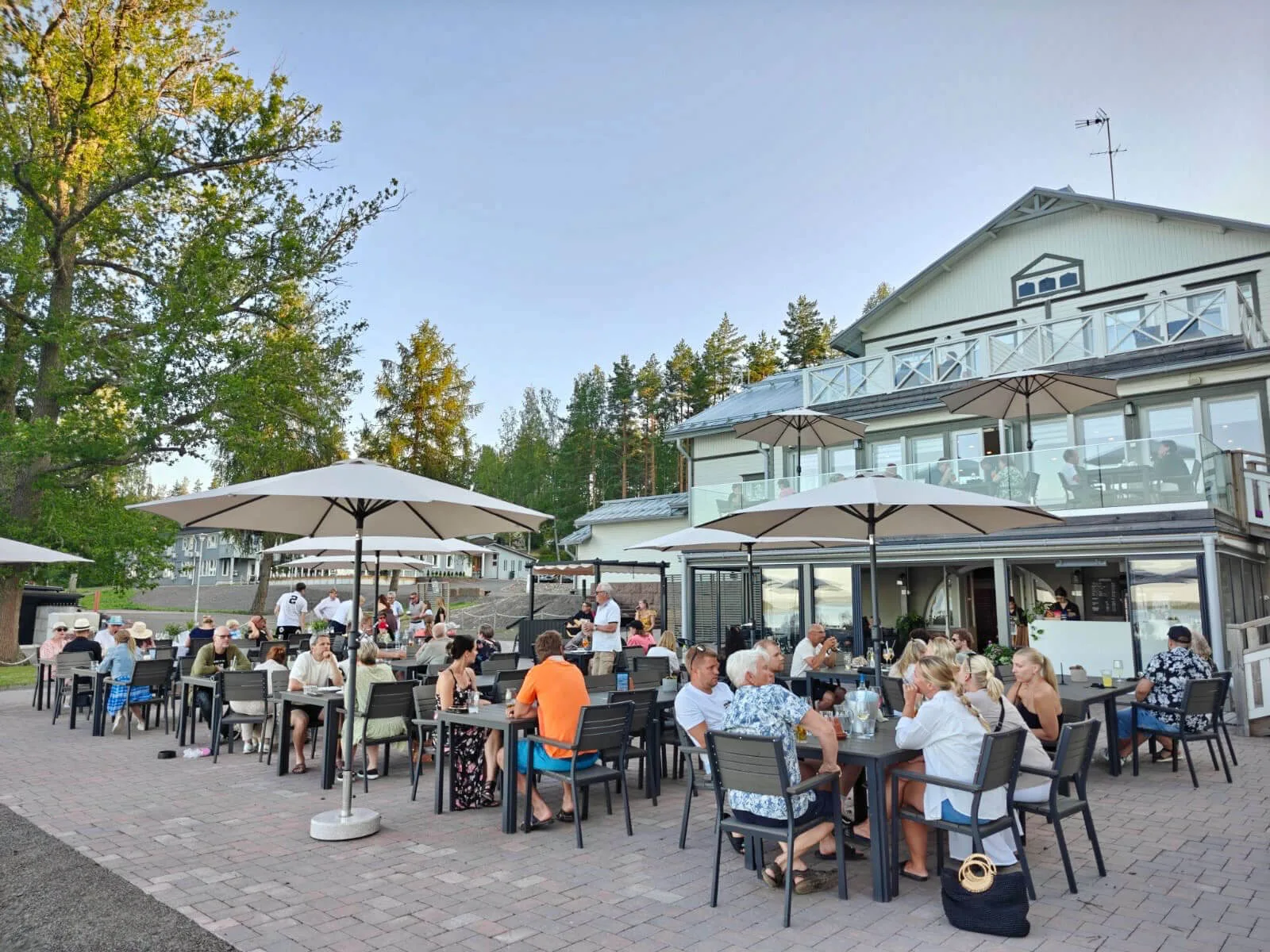 Representative hotel space: Outdoor dining area with tables and umbrellas beside a multi-story building.