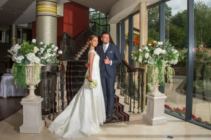 Representative hotel space: A couple poses beside a staircase decorated with floral arrangements.