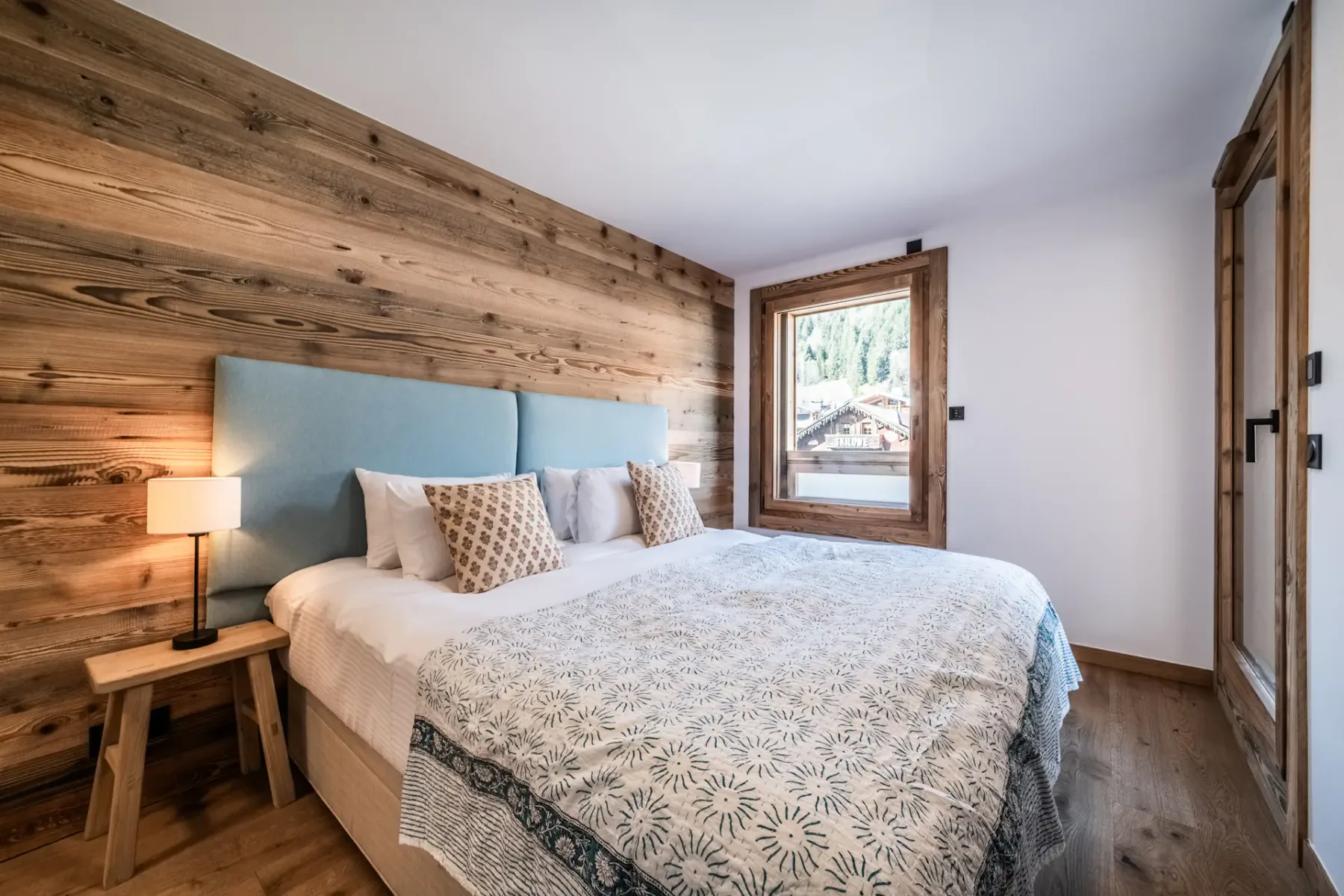 Un dormitorio con una cama grande, una pared de madera y una ventana.