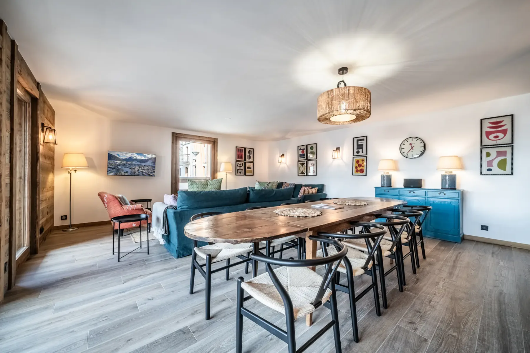 Un área de comedor y sala con una mesa larga, asientos y gabinetes azules.