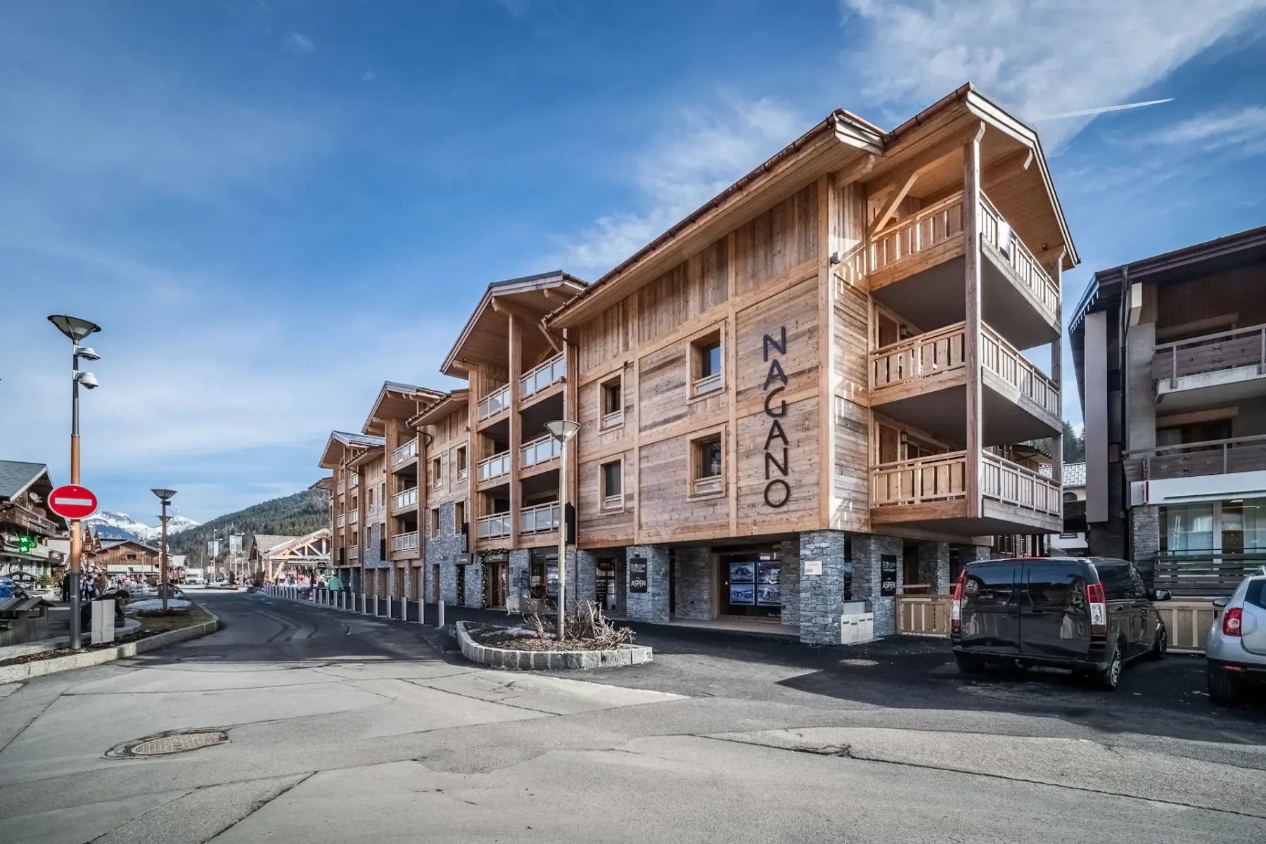 Zona común: Una calle bordeada de edificios de madera de varios pisos y vehículos estacionados.
