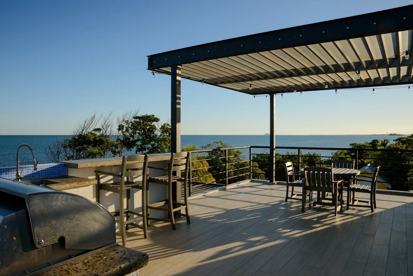Zona común: Una terraza exterior con vistas al mar y asientos bajo una pérgola.