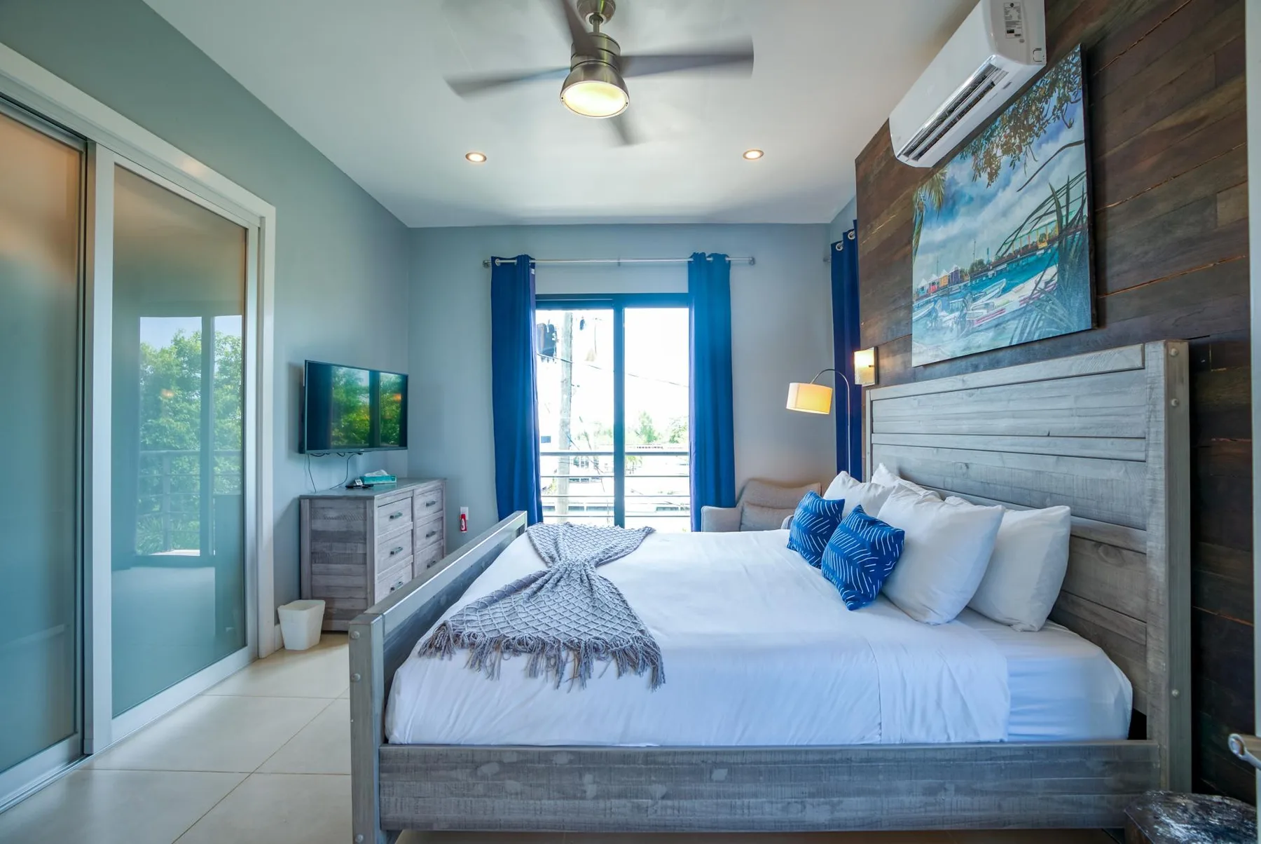 Un dormitorio con una cama grande, cortinas azules y un ventilador de techo.