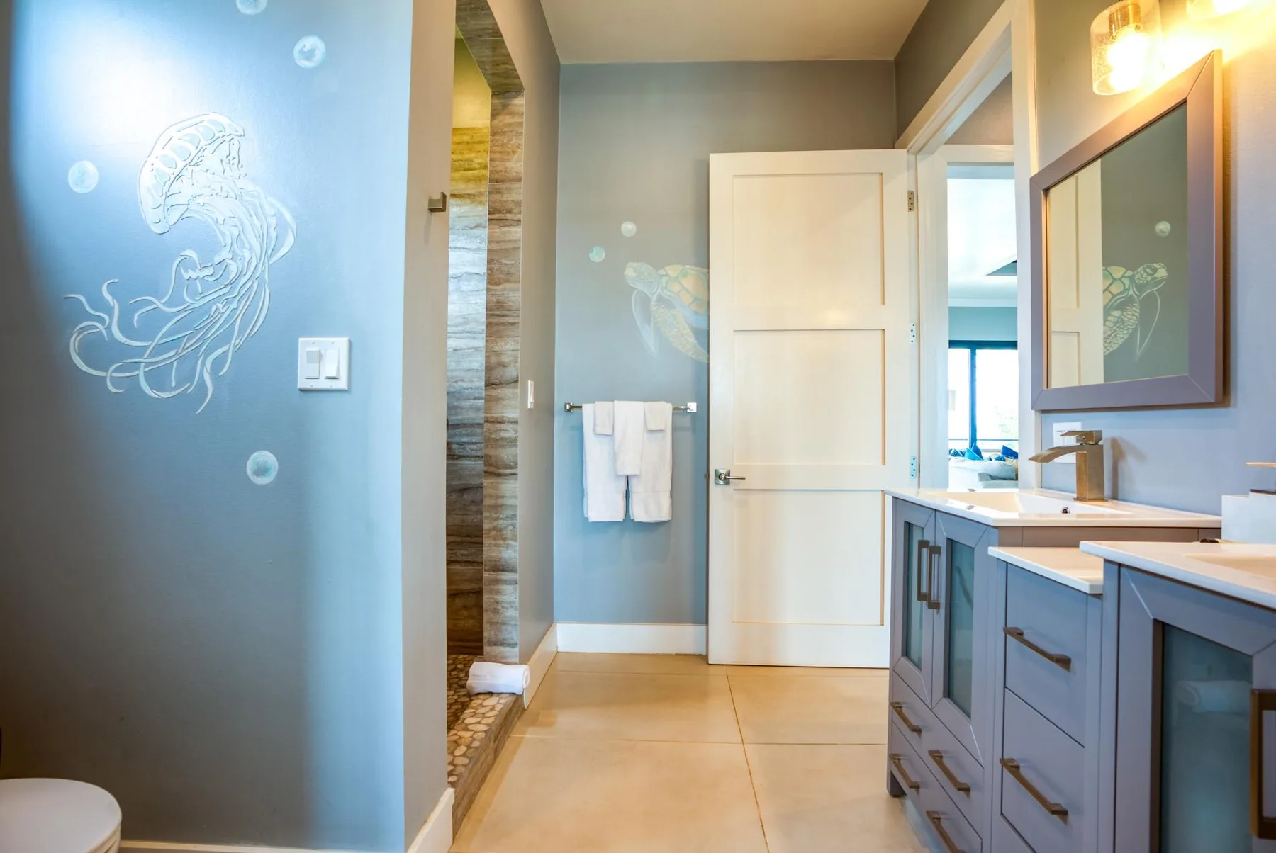 Un baño con un mueble de lavabo largo, un espejo de pared y la puerta abierta.