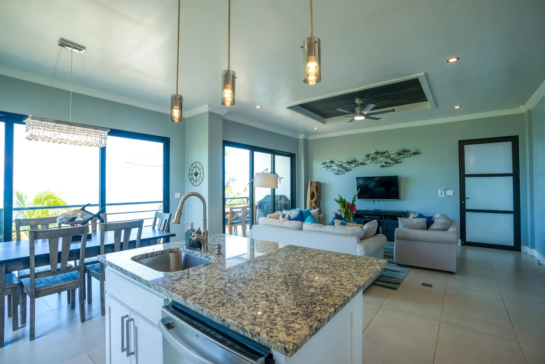 Una sala de estar y cocina abiertas, con una mesa de comedor junto a grandes ventanas.